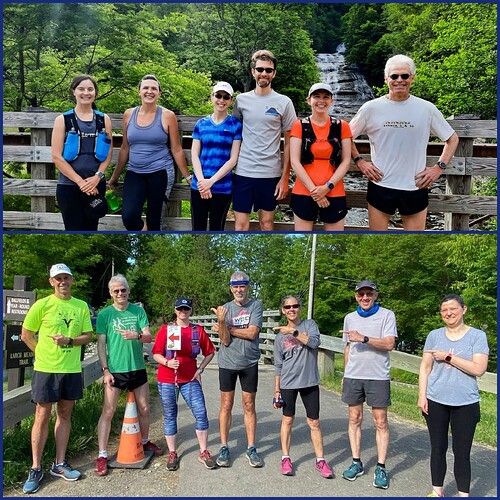 Runners in brightly colored clothes stand on a bridge in front of a waterfall.