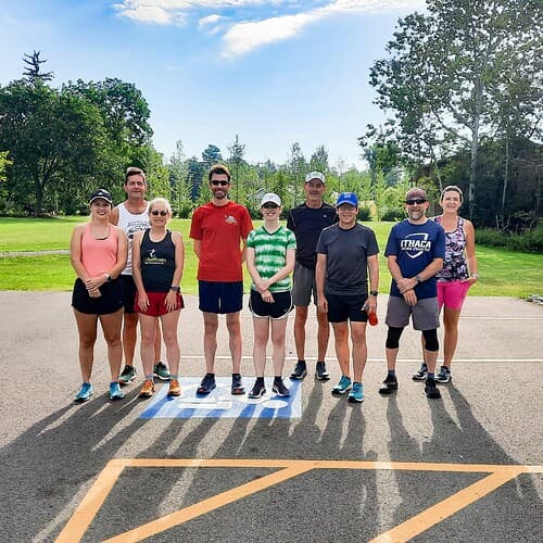 A group of runners pose for a picture in the sun.